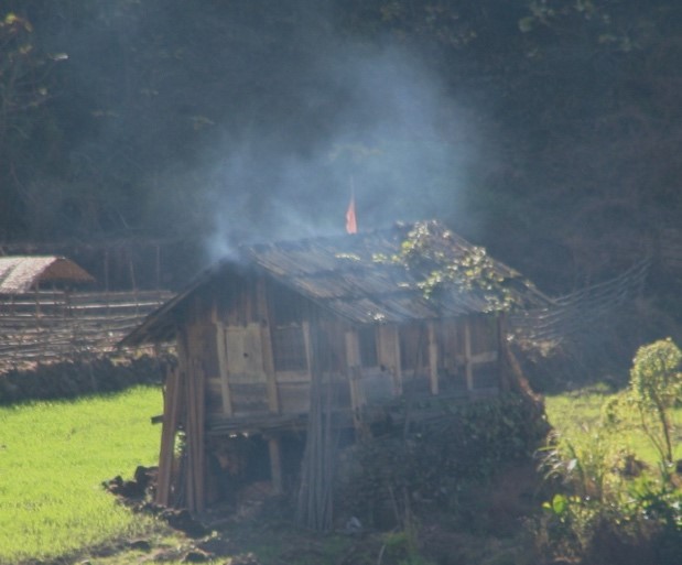 Eine Hütte aus einiger Entfernung, durch das Dach quillt Rauch nach draußen.